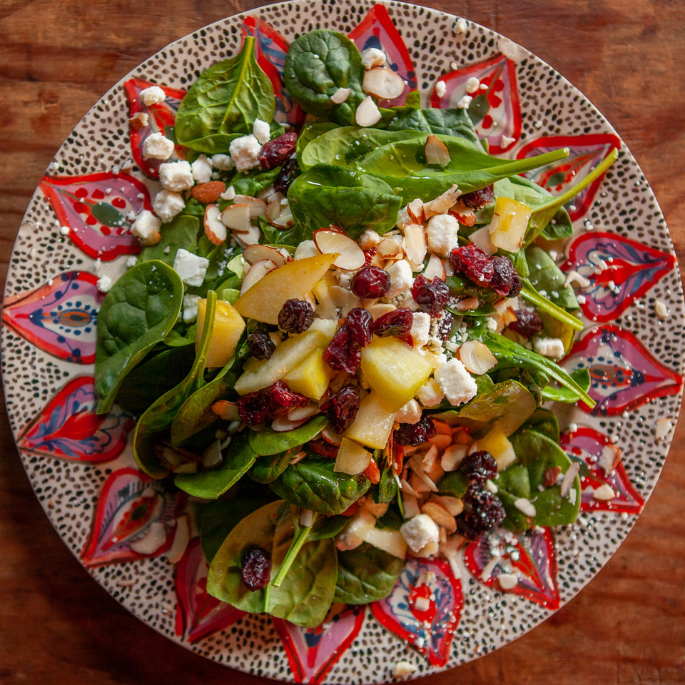 Spinach salad with cranberries, almonds, feta, and pear on a decorative plate at The Blues Burgers.